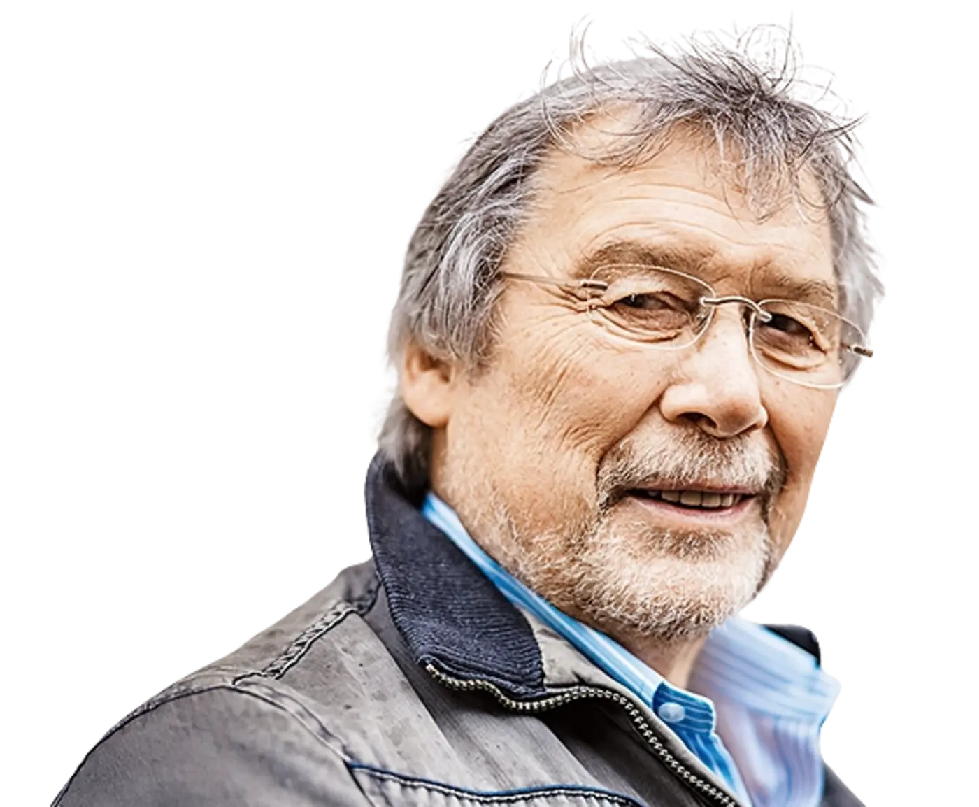 Ein älterer Mann mit grau meliertem Haar, Brille und einem kurzen grauen Bart blickt freundlich in die Kamera. Er trägt eine graue Freizeitjacke mit Reißverschluss über einem blau-weiß gestreiften Hemd vor einem neutralen weißen Hintergrund.