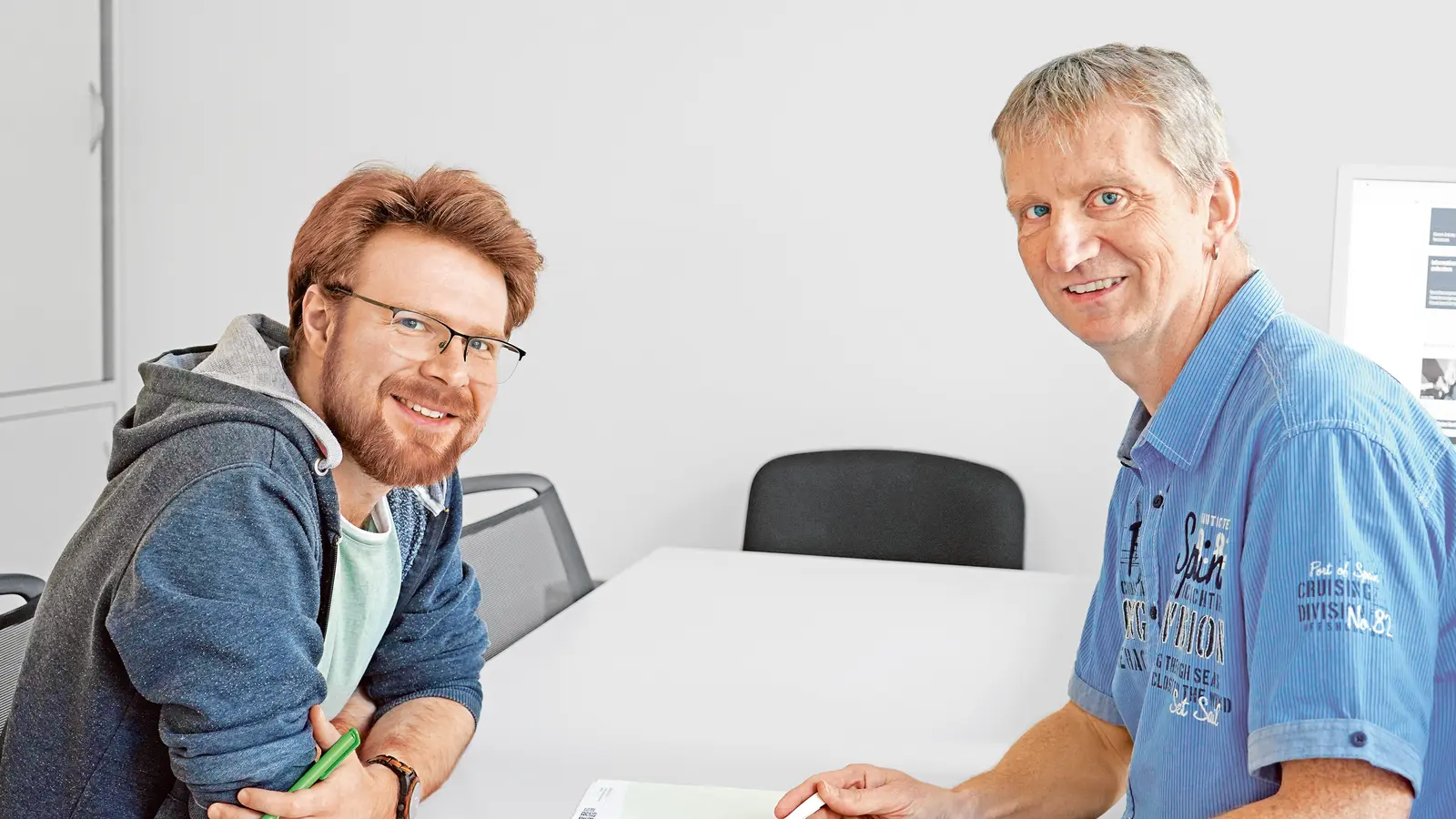 Zwei Männer sitzen während einer Kundenberatung am Tisch.