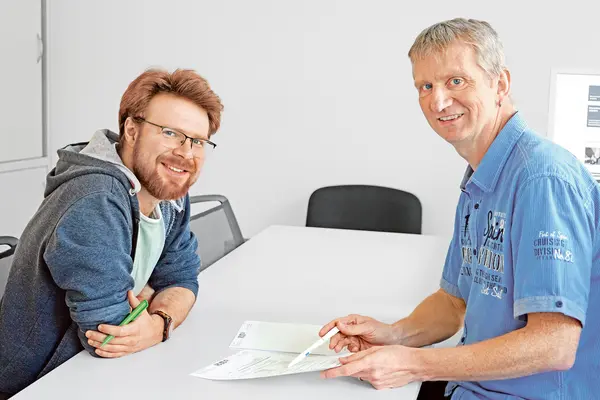 Zwei Männer sitzen während einer Kundenberatung am Tisch. 