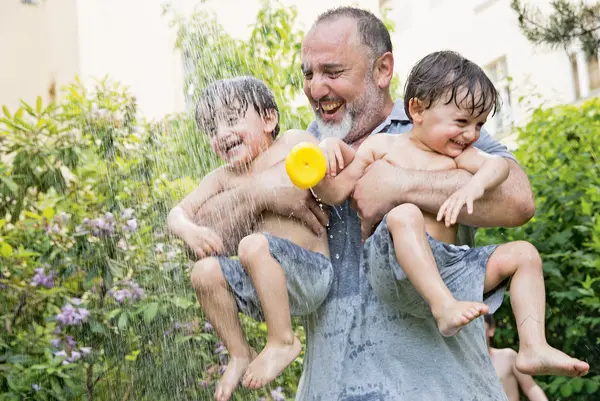 Ein Vater spielt lachend mit seinen zwei Kindern unter Wasser.