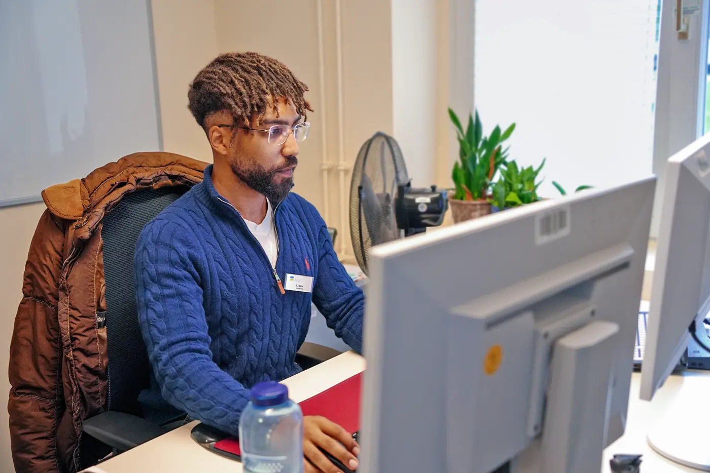 Ein Mann sitzt am Arbeitstisch und schaut auf den Bildschirm.