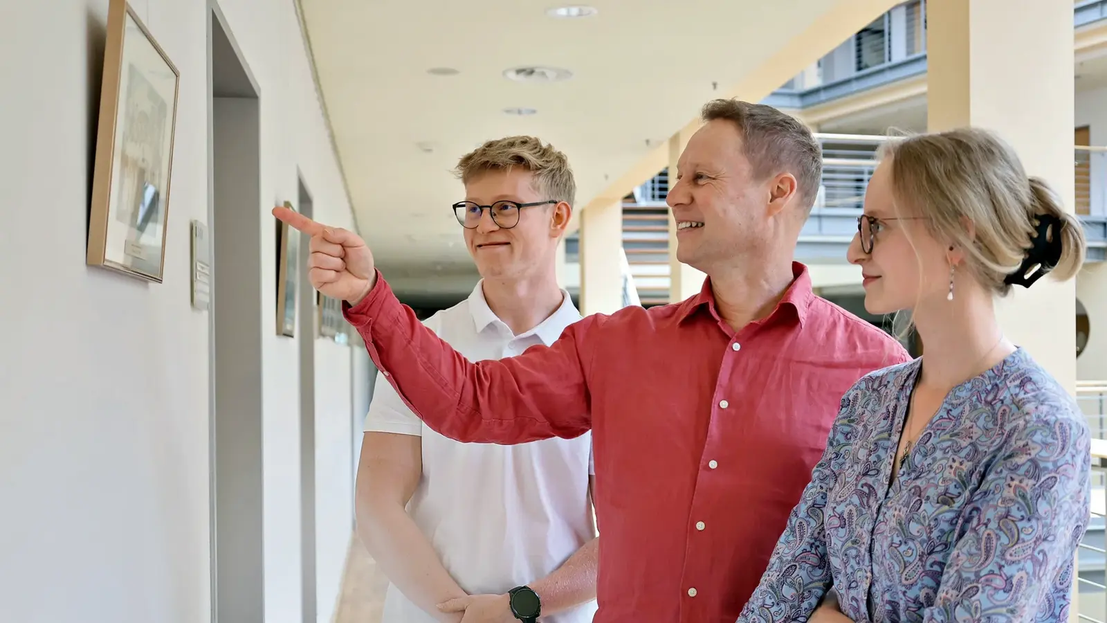 Ein Vater zeigt seinen zwei Kindern ein Foto an der Wand.