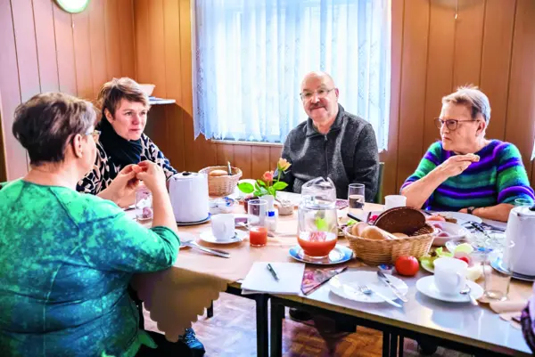 Vier ältere Personen, die gemeinsam an einem Tisch sitzen und frühstücken.