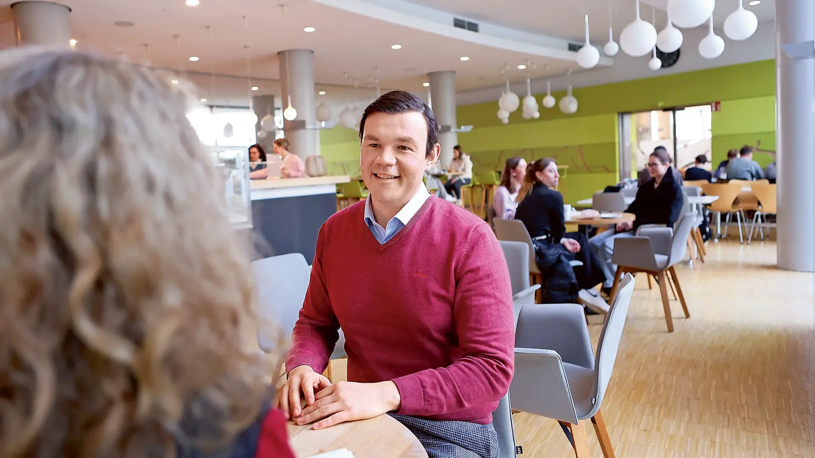 Auf dem Bild sitzt ein Mann in einem Café und führt ein Gespräch.