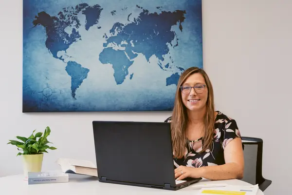 Isabelle Hennes ist am Arbeitstisch und lächelt in die Kamera. 