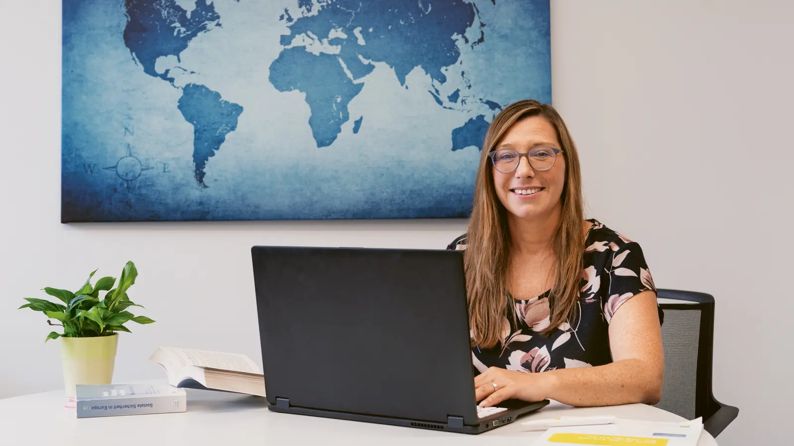 Isabelle Hennes ist am Arbeitstisch und lächelt in die Kamera. 