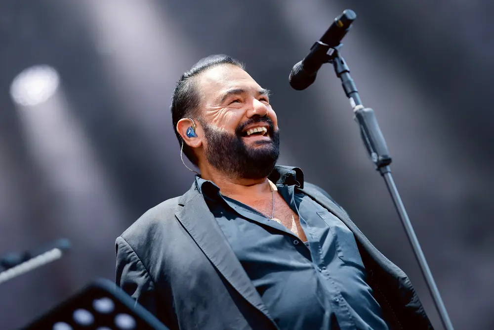 Marian Gold steht lächeln am Mikrofon.