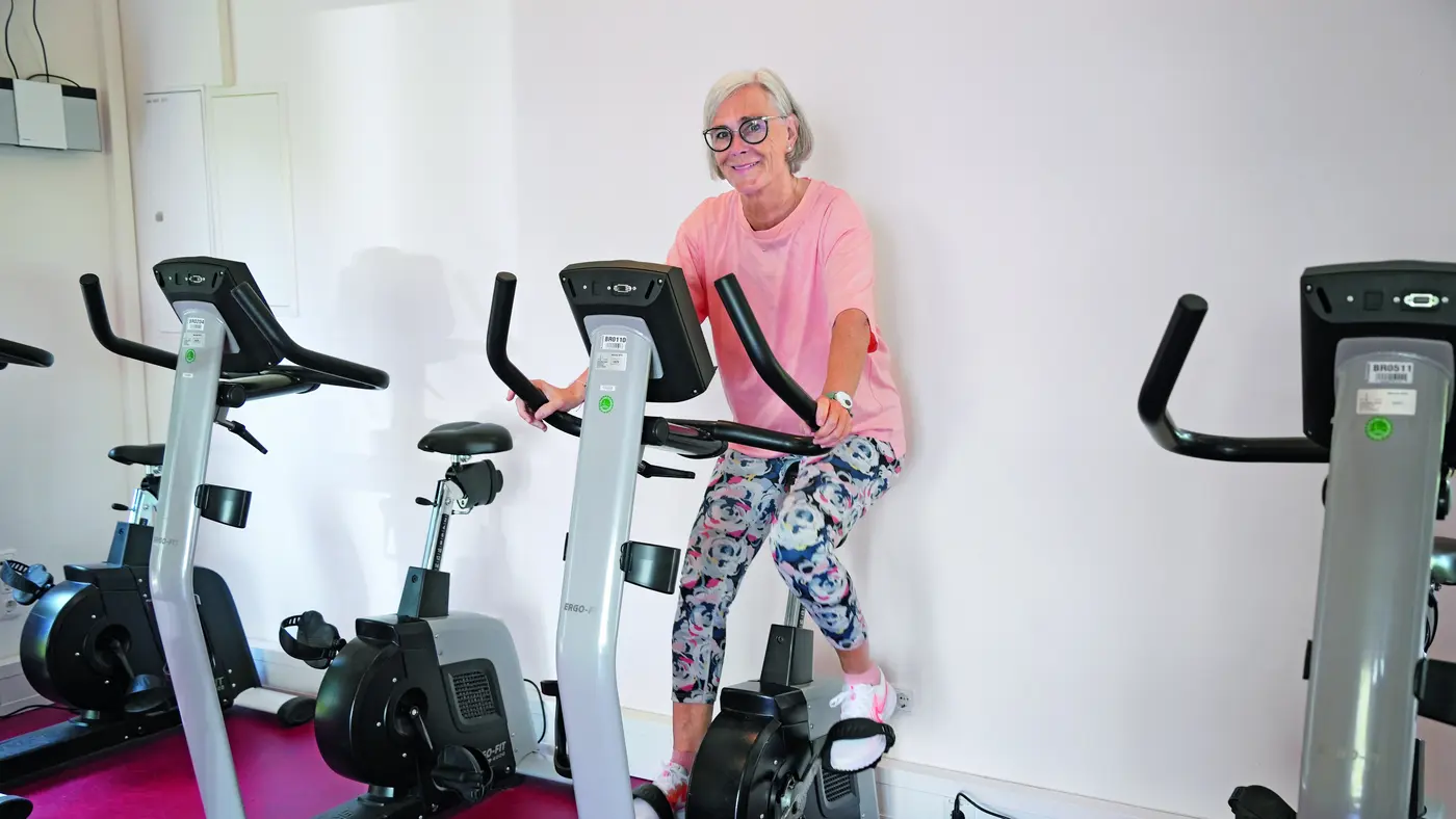 Eine ältere Dame trainiert auf einem Fahrradtrainer.