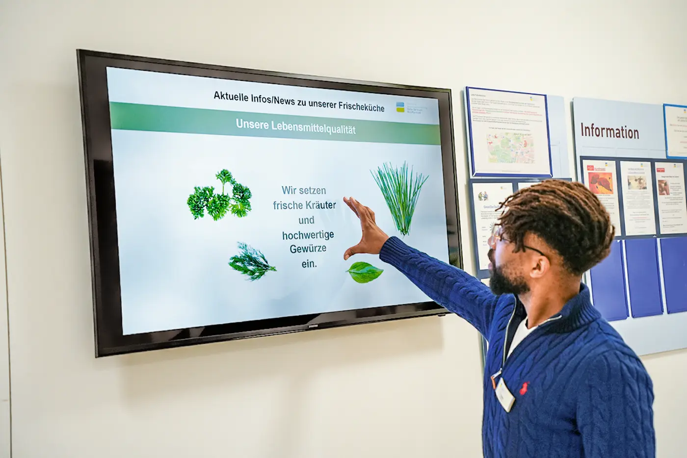 Ein Mann, der mit seinen Händen etwas vor einem Bildschirm zeigt.