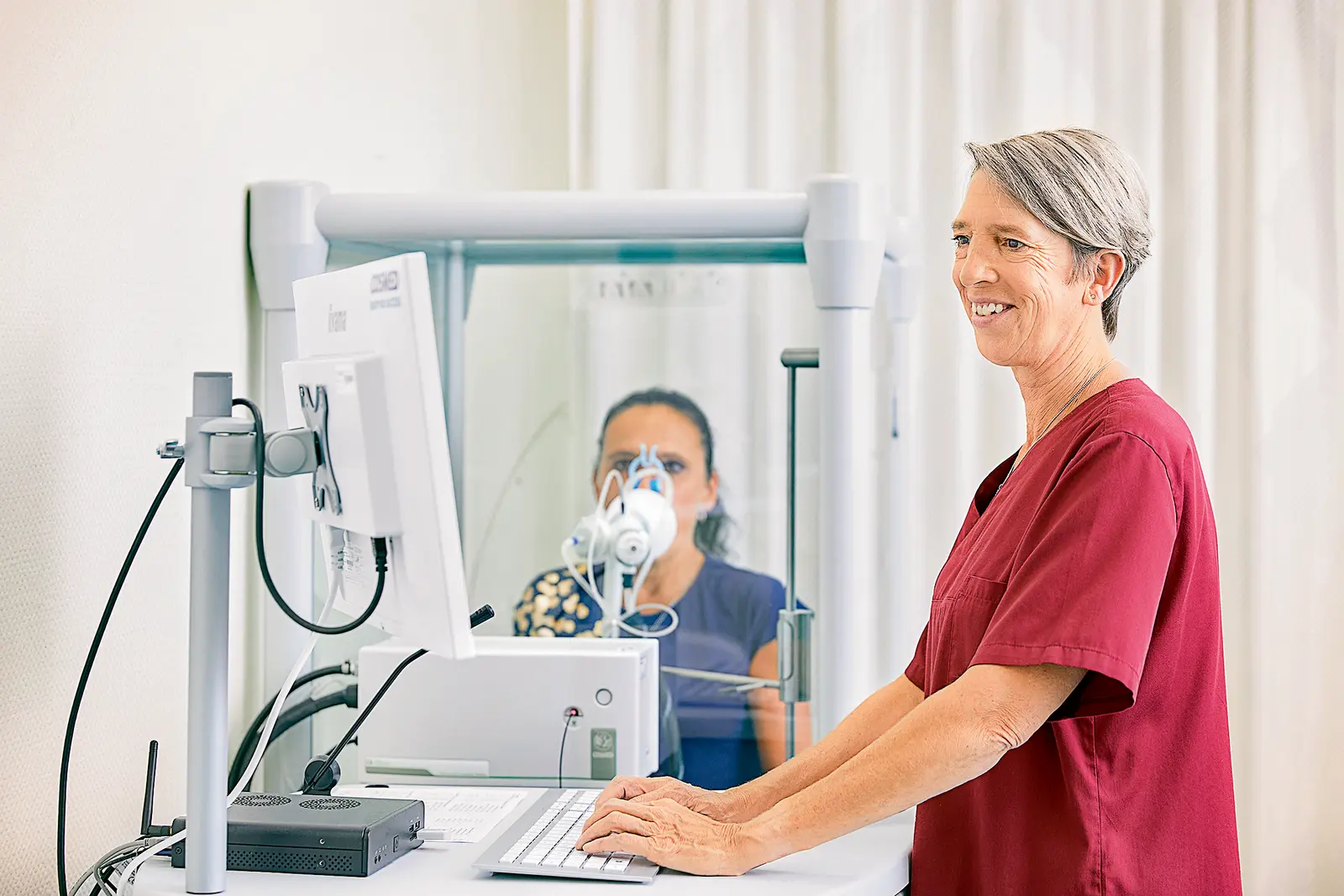 Eine medizinische Fachkraft leitet einer Patientin mit einem speziellen Gerät bei einem Atemtraining an.