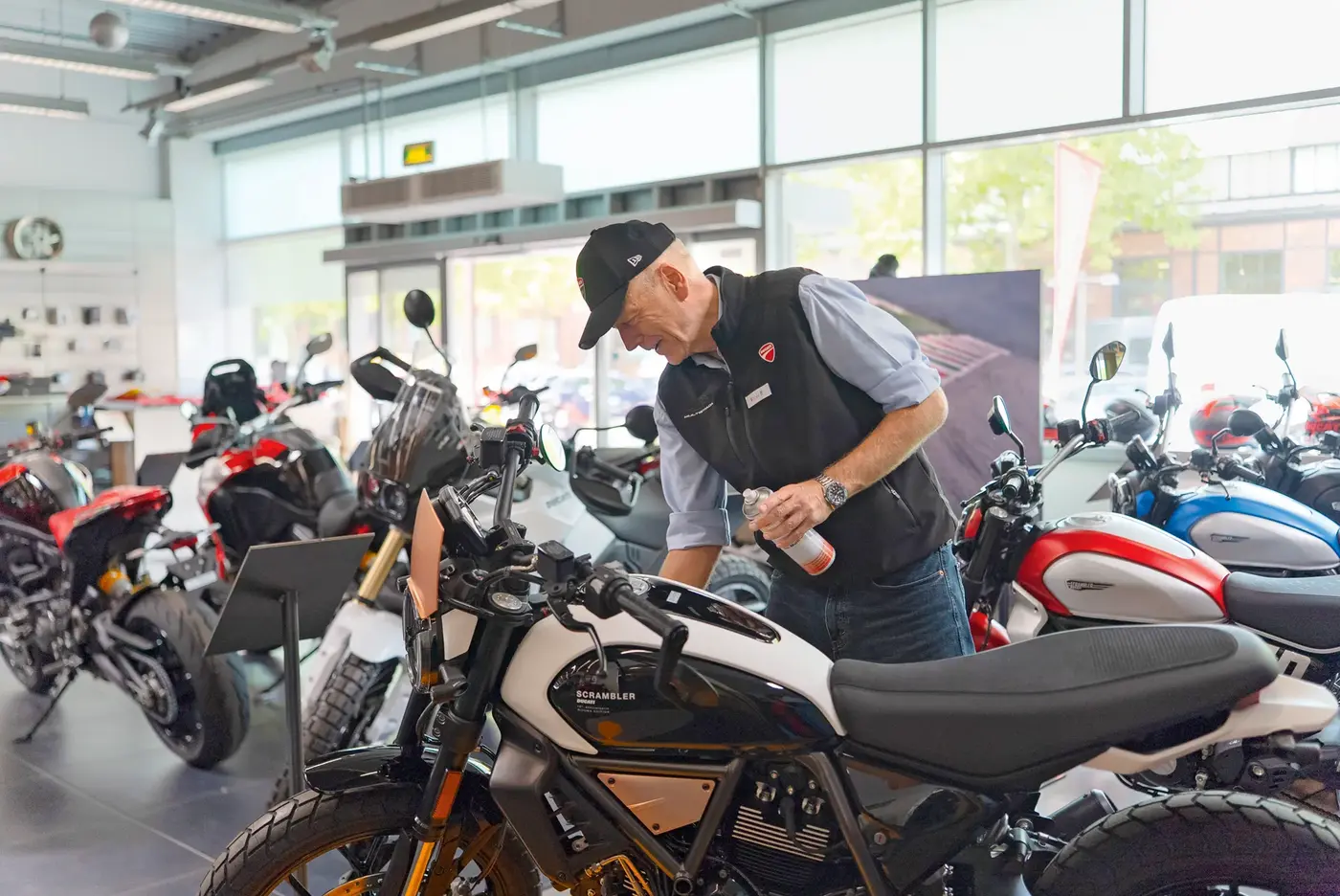 Ein älterer Herr bastelt an seinem Motorrad herum.