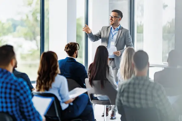 Ein Mann referiert vor einer Menschengruppe.