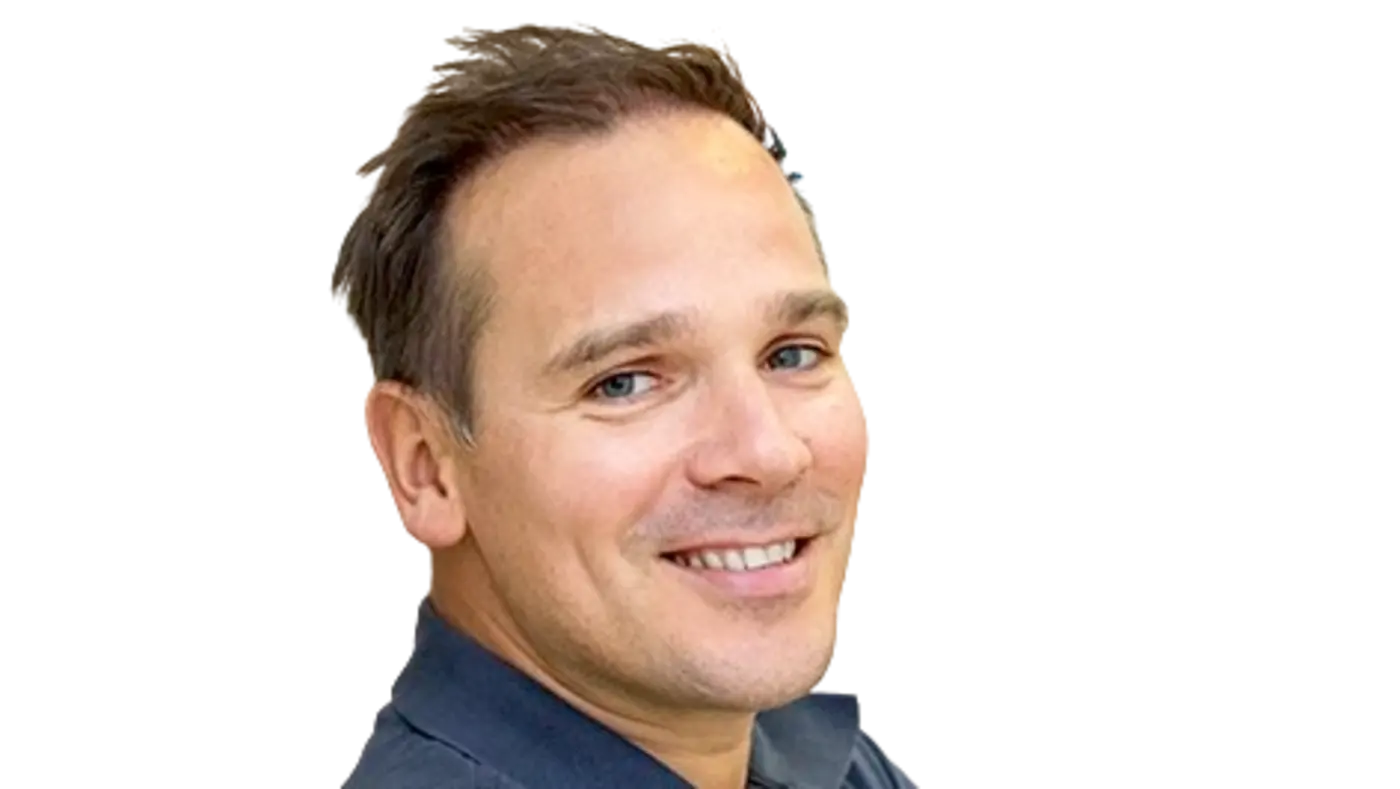 Porträt eines Mannes mit kurzen braunen Haaren und blauem Hemd, der freundlich in die Kamera lächelt.