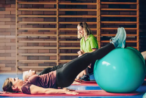 Zwei Frauen führen mit Gymnastikbällen Übungen durch.