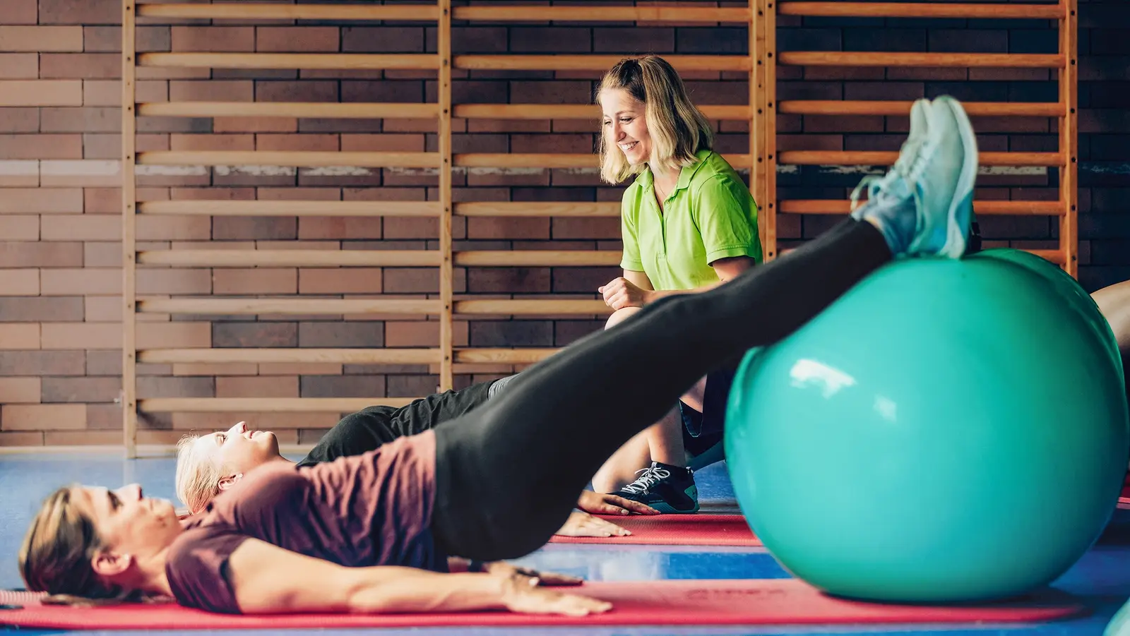 Zwei Frauen führen mit Gymnastikbällen Übungen durch.