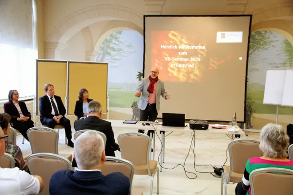 Ein Mann hält vor mehreren Personen eine Präsentation.