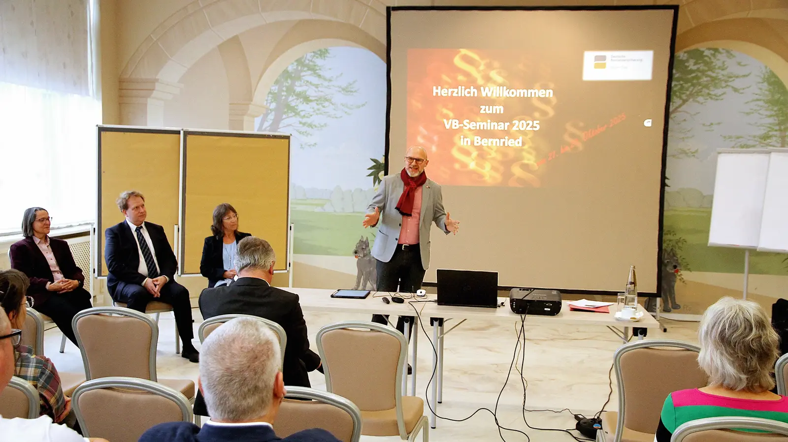 Ein Mann hält vor mehreren Personen eine Präsentation.