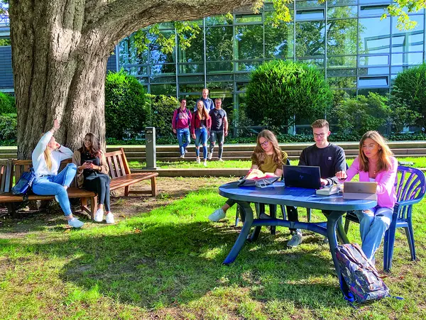 Studierende lernen und unterhalten sich im Freien auf einem Campus.