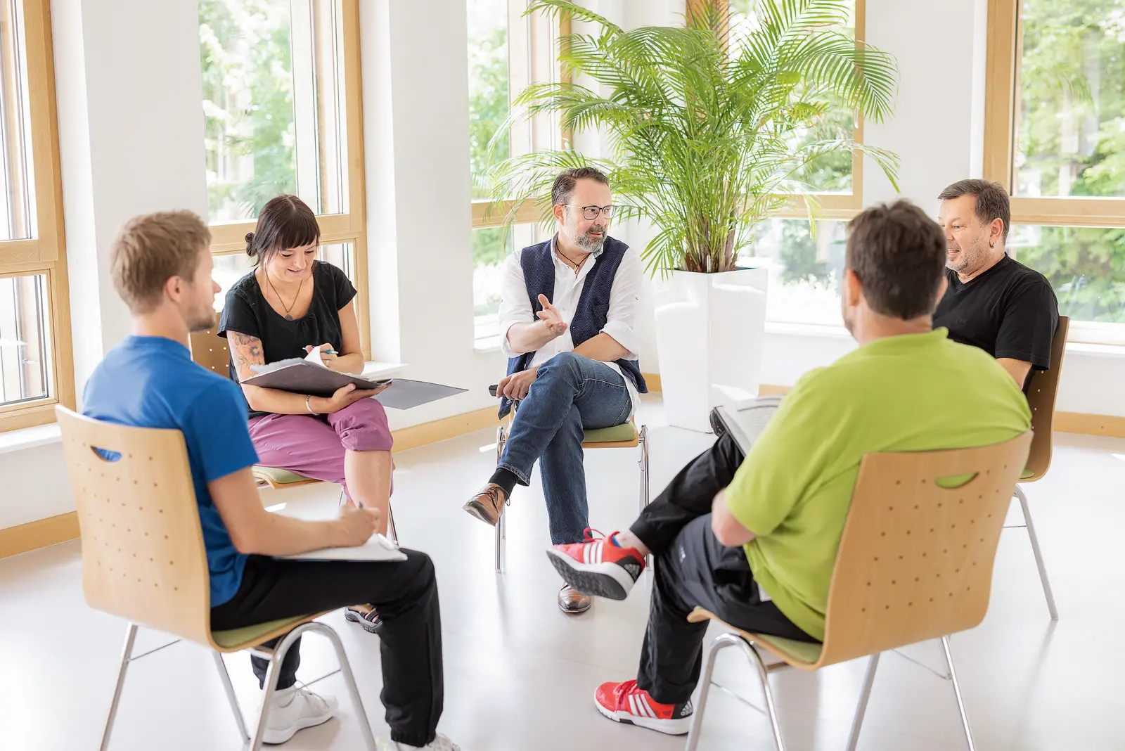 Fünf Personen, die im Stuhlkreis sitzen und sich in einer Gesprächsrunde austauschen.