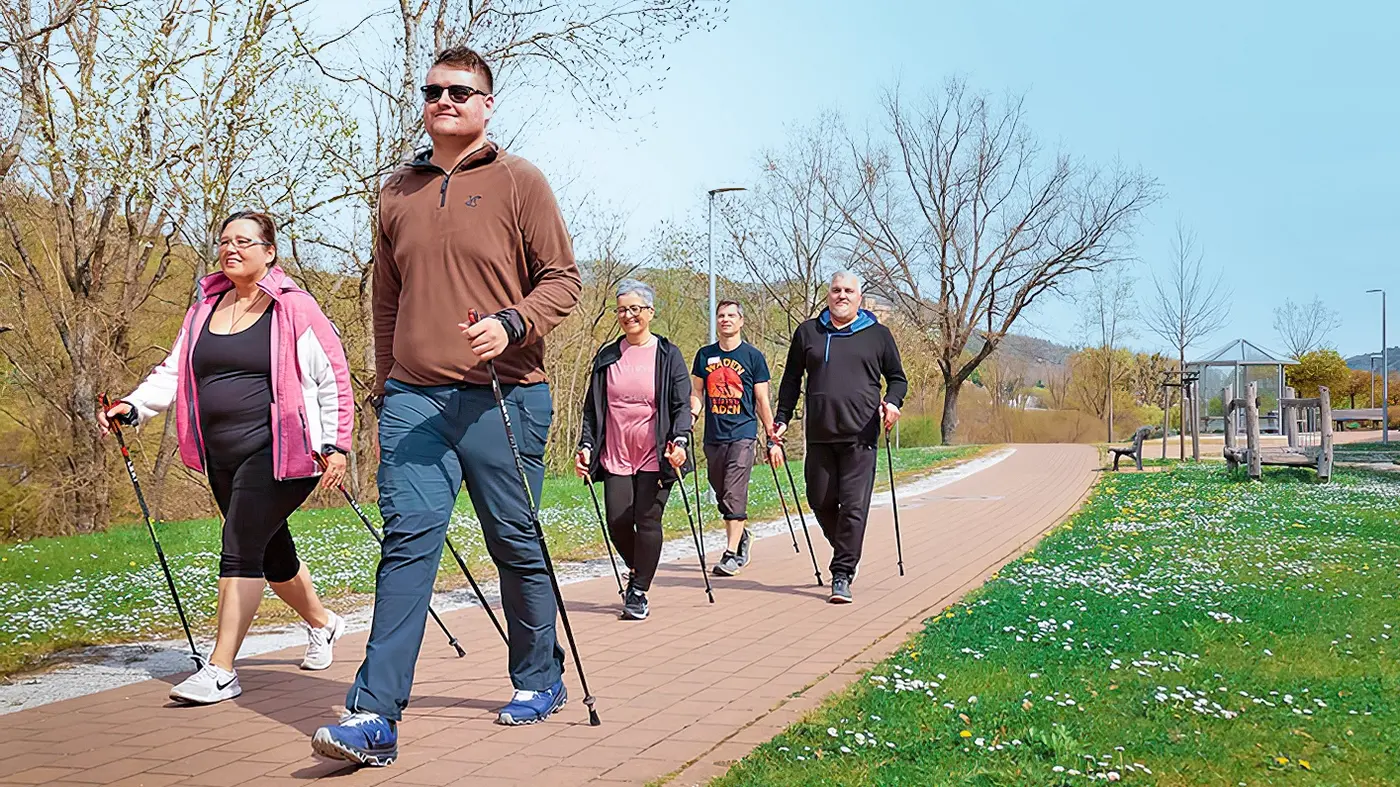 Mit Wanderstöcken ausgerüstet, spaziert eine Gruppe durch die Natur.