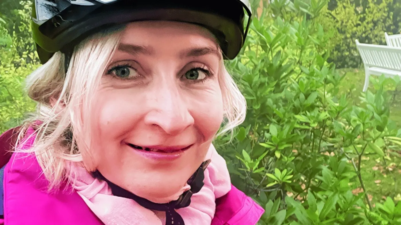 Eine Dame mit einem Fahrradhelm auf dem Kopf, macht ein Selfie von sich selber.