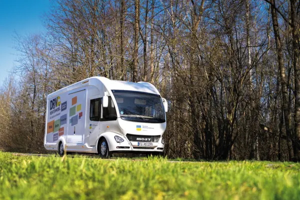 Ein Rentenmobil fährt durch ein Waldgebiet.