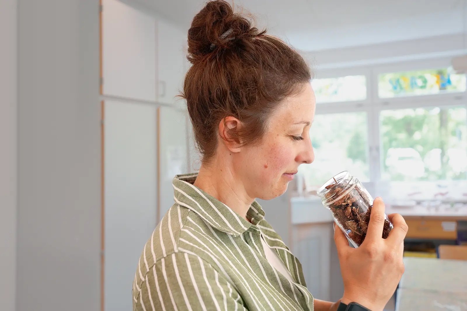 Eine Dame riecht an einem Glas mit Hopfendolden.